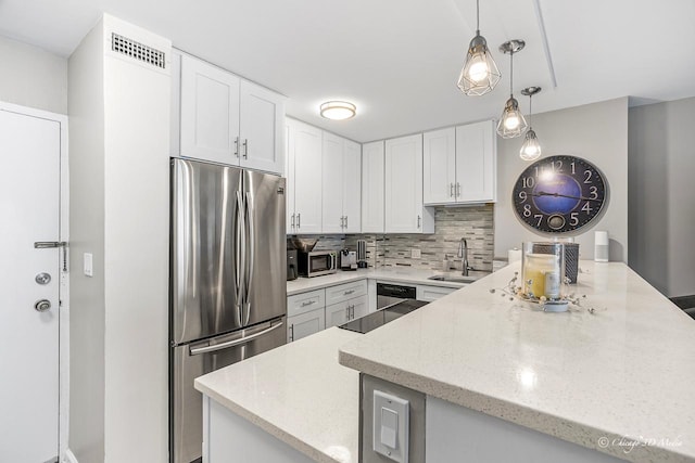 kitchen featuring stainless steel appliances, a sink, a peninsula, white cabinets, and tasteful backsplash