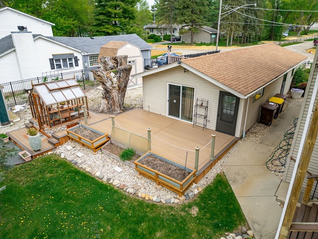 rear view of house with a deck, a vegetable garden, and a shingled roof