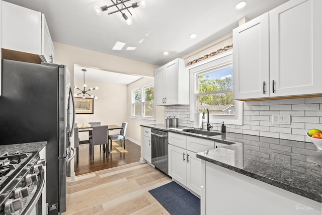 806 71st St, Darien, IL 60561 - kitchen featuring stainless steel appliances, a chandelier, light wood-style floors, decorative backsplash, and a sink