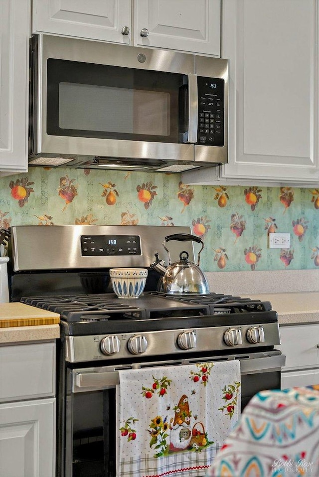 kitchen featuring appliances with stainless steel finishes, white cabinetry, and light countertops