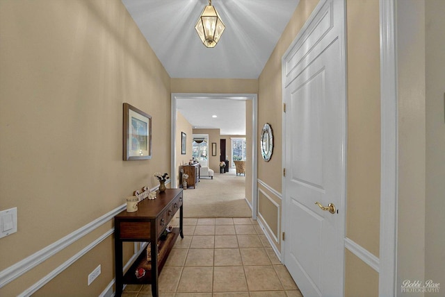 hall featuring light tile patterned flooring, light carpet, and baseboards