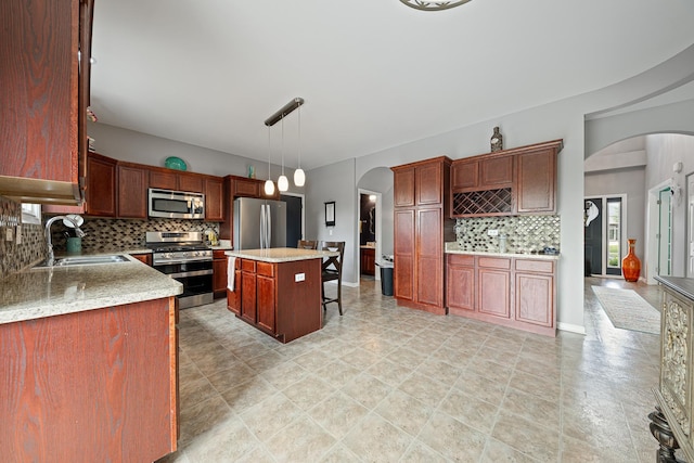 2274 Scotsglen Dr, New Lenox, IL 60451 - kitchen featuring appliances with stainless steel finishes, arched walkways, a sink, backsplash, and a breakfast bar