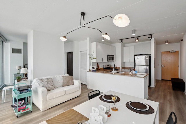 611 S Wells St Unit 2801, Chicago, IL 60607 - kitchen featuring stainless steel appliances, wood finished floors, a peninsula, white cabinets, and a sink
