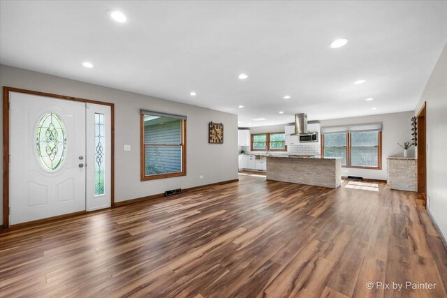 foyer with dark wood finished floors, recessed lighting, and baseboards
