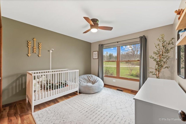 bedroom featuring baseboards, wood finished floors, and ceiling fan