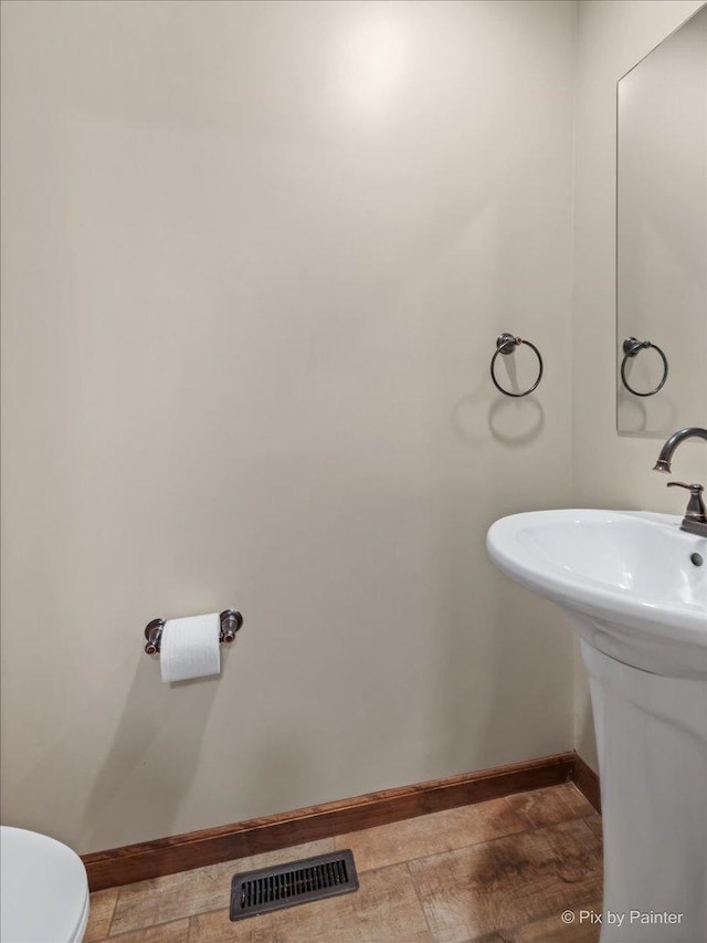 bathroom with baseboards, toilet, and a sink