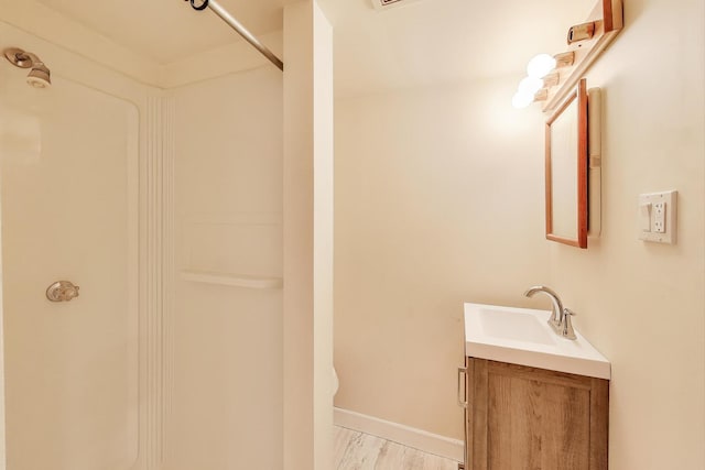 bathroom featuring vanity, a shower, and wood finished floors