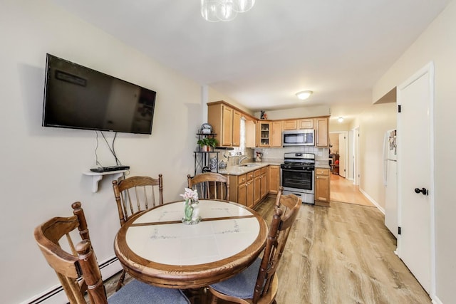 dining space with light wood finished floors and baseboard heating