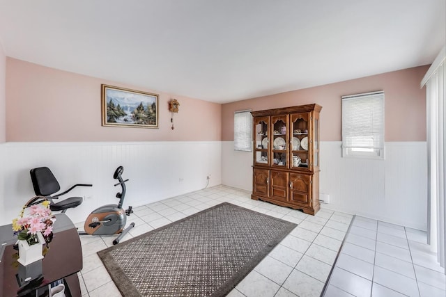 workout room featuring a wainscoted wall and light tile patterned flooring