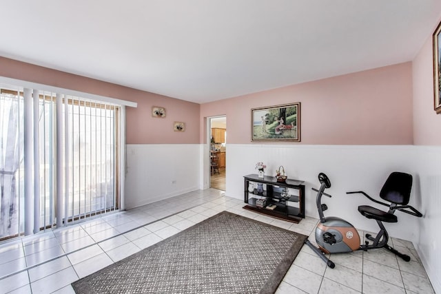 exercise area with tile patterned floors and a wainscoted wall
