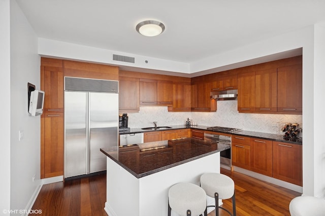 60 E Monroe St Unit 6203, Chicago, IL 60603 - kitchen featuring stainless steel appliances, under cabinet range hood, dark wood finished floors, brown cabinetry, and a sink