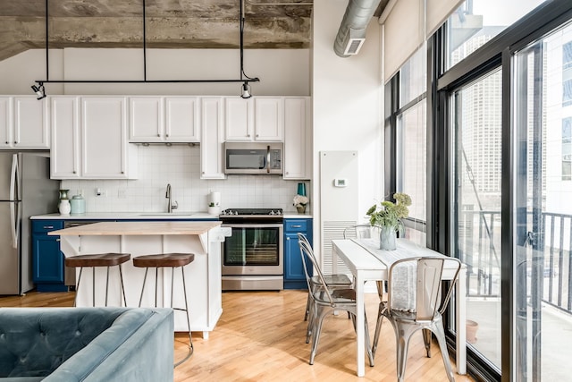 210 S Desplaines St Unit 402, Chicago, IL 60661 - kitchen with appliances with stainless steel finishes, blue cabinetry, a sink, light wood-style flooring, and decorative backsplash