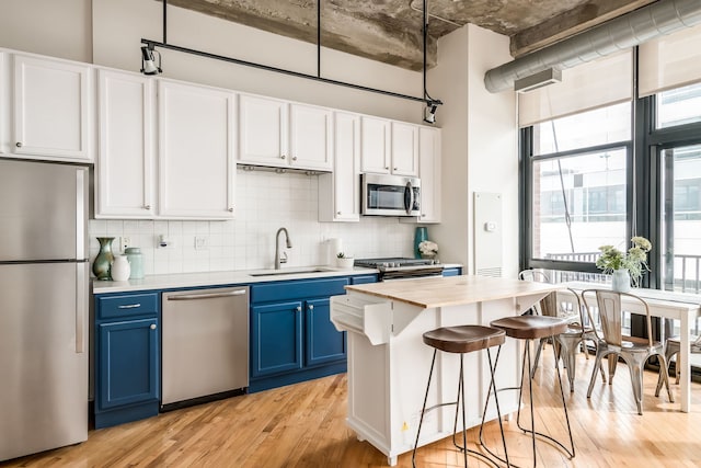 210 S Desplaines St Unit 402, Chicago, IL 60661 - kitchen featuring stainless steel appliances, blue cabinetry, a sink, light wood finished floors, and light countertops