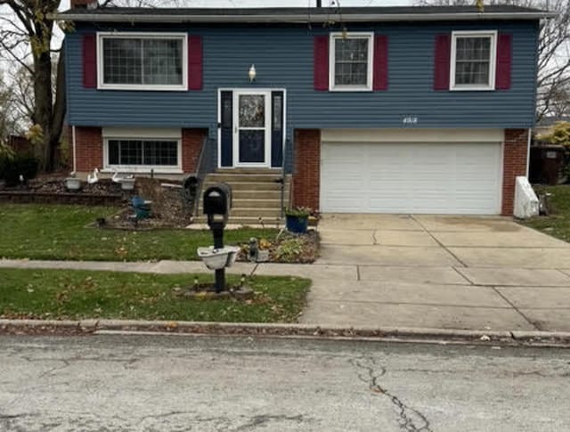 split foyer home featuring brick siding, a garage, concrete driveway, entry steps, and a front yard