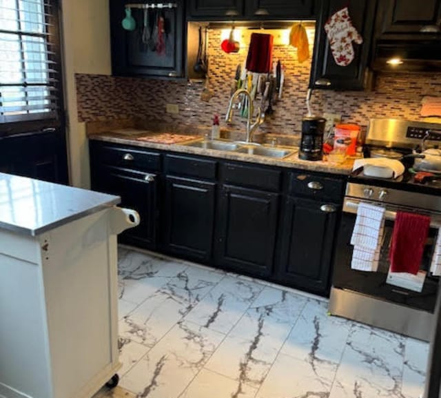kitchen with stainless steel gas range, light marble finish floors, a sink, dark cabinets, and exhaust hood