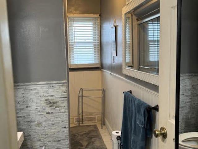 bathroom featuring toilet and a wainscoted wall