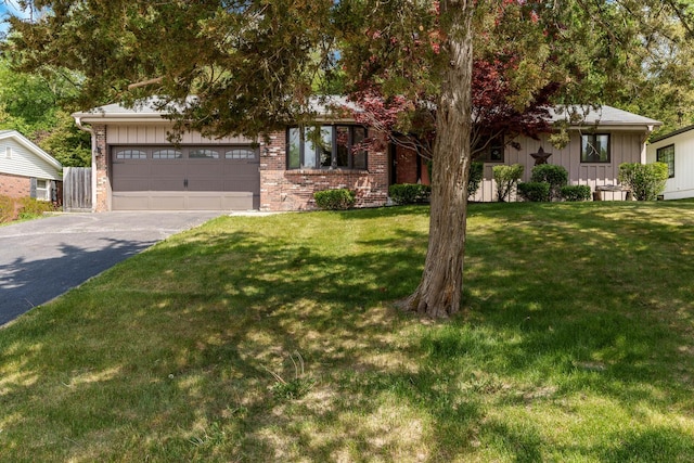 4922 Brookview Rd, Rockford, IL 61107 - view of property hidden behind natural elements featuring asphalt driveway, board and batten siding, a garage, a front lawn, and brick siding