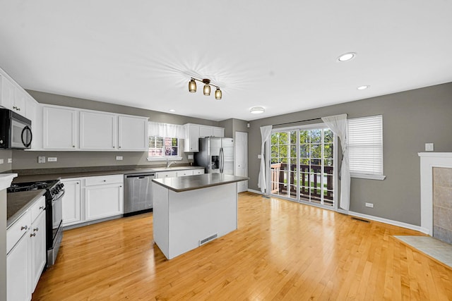 62 E Emma Ct, Palatine, IL 60067 - kitchen featuring black appliances, a center island, dark countertops, light wood-style flooring, and a sink