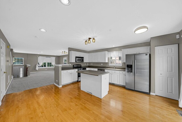 62 E Emma Ct, Palatine, IL 60067 - kitchen with appliances with stainless steel finishes, light wood-style floors, white cabinets, dark countertops, and a kitchen island