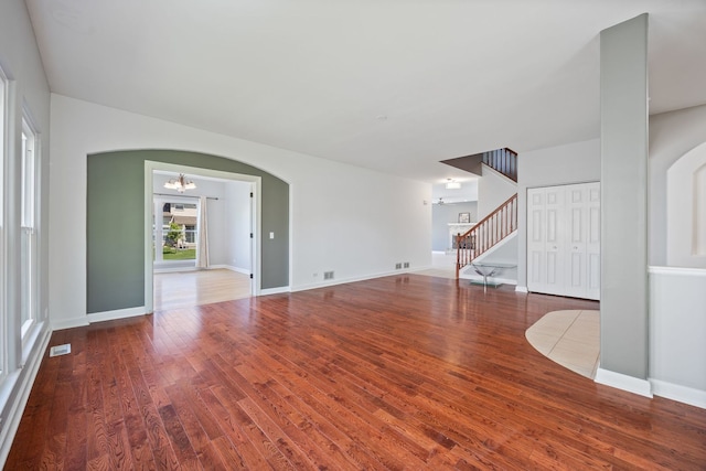 9231 N Natchez Ave, Morton Grove, IL 60053 - unfurnished living room with a chandelier, wood finished floors, arched walkways, stairs, and baseboards