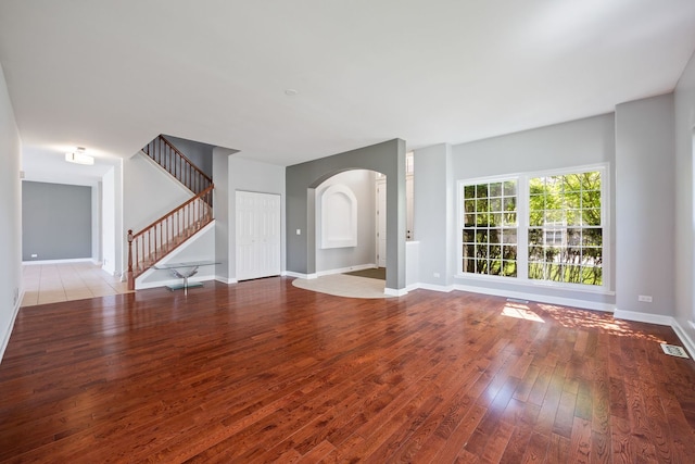 9231 N Natchez Ave, Morton Grove, IL 60053 - unfurnished living room with wood-type flooring, arched walkways, baseboards, and stairs