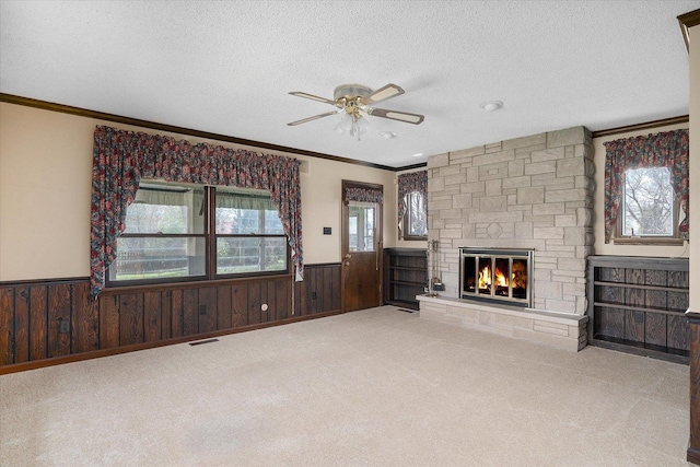 745 Konen Ave, Aurora, IL 60505 - unfurnished living room with wainscoting, a ceiling fan, a fireplace, ornamental molding, and a textured ceiling