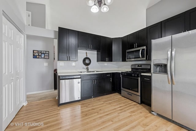 1247 Trinity Dr, Carol Stream, IL 60188 - kitchen with appliances with stainless steel finishes, dark cabinets, light countertops, light wood-style floors, and a chandelier