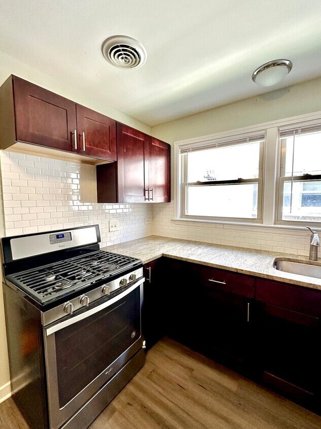 8137 Keating Ave, Skokie, IL 60076 - kitchen with stainless steel range with gas cooktop, a sink, wood finished floors, dark brown cabinets, and tasteful backsplash