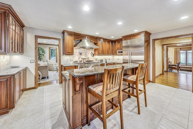 6425 N Tower Ct, Lincolnwood, IL 60712 - kitchen featuring wall chimney exhaust hood, stone countertops, tasteful backsplash, recessed lighting, and baseboards
