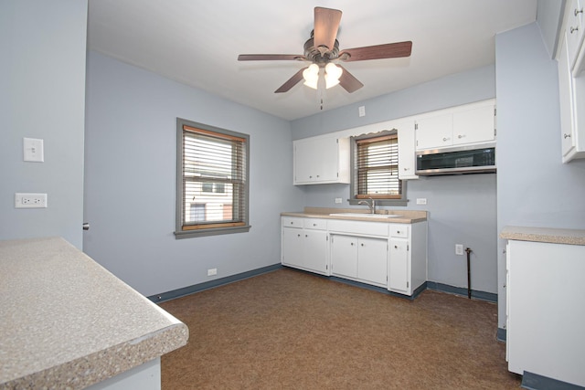 5533 S Menard Ave, Chicago, IL 60638 - kitchen featuring stainless steel microwave, a sink, ceiling fan, dark carpet, and white cabinetry