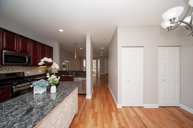 kitchen featuring appliances with stainless steel finishes, light wood-style floors, backsplash, dark brown cabinets, and a sink