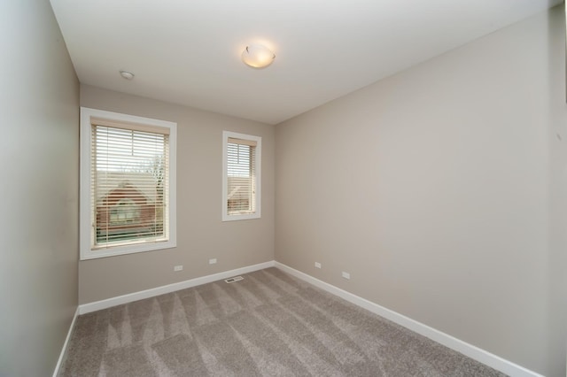 spare room featuring baseboards, light colored carpet, and a smoke detector