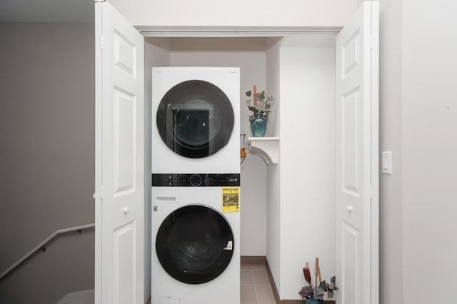 laundry area with stacked washer / drying machine and tile patterned floors