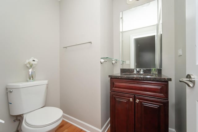 bathroom with toilet, vanity, baseboards, and wood finished floors