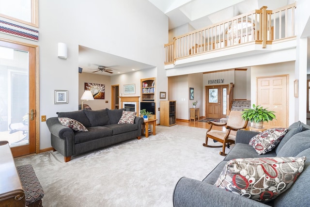 56 Huntsman Ln, Plano, IL 60545 - living area featuring a ceiling fan, a high ceiling, baseboards, a fireplace, and carpet flooring