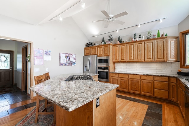 56 Huntsman Ln, Plano, IL 60545 - kitchen featuring track lighting, stainless steel appliances, vaulted ceiling, light stone countertops, and a kitchen island
