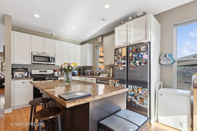 1845 N Marshfield Ave, Chicago, IL 60622 - kitchen with stainless steel appliances, a breakfast bar, light stone countertops, white cabinets, and recessed lighting