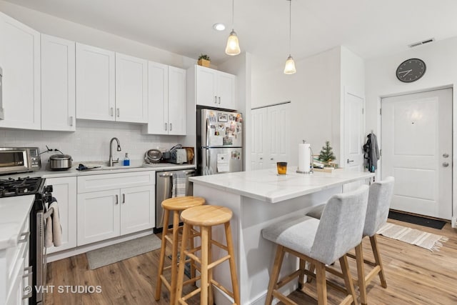 1845 N Marshfield Ave, Chicago, IL 60622 - kitchen with stainless steel appliances, a sink, a kitchen breakfast bar, light wood finished floors, and tasteful backsplash