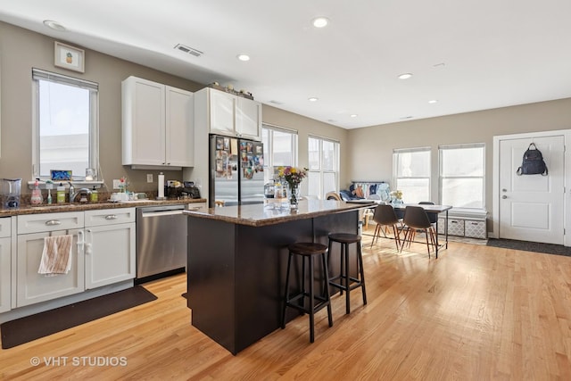 1845 N Marshfield Ave, Chicago, IL 60622 - kitchen with appliances with stainless steel finishes, a sink, light wood-type flooring, a breakfast bar area, and white cabinets