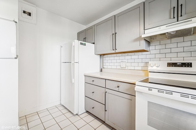 kitchen with white appliances, under cabinet range hood, gray cabinets, backsplash, and light countertops