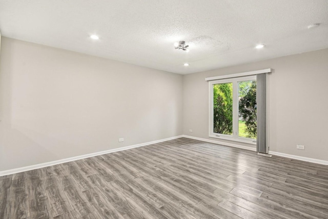 unfurnished room featuring wood finished floors, baseboards, a textured ceiling, recessed lighting, and a smoke detector