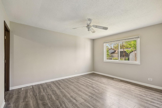 spare room featuring a textured ceiling, wood finished floors, ceiling fan, and baseboards
