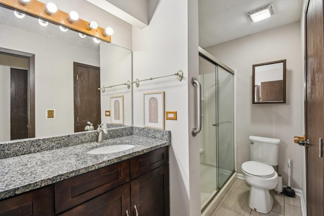 full bath featuring toilet, a stall shower, vanity, tile patterned flooring, and baseboards