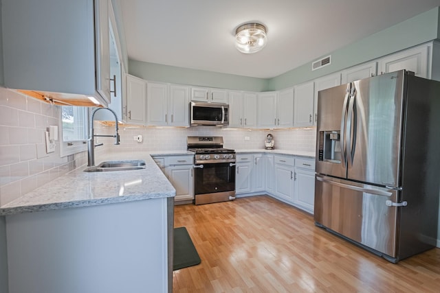 1706 Childs St, Wheaton, IL 60187 - kitchen with stainless steel appliances, a sink, decorative backsplash, light wood finished floors, and white cabinetry