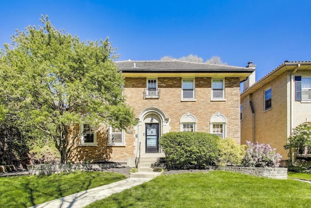colonial-style house featuring a front yard and brick siding