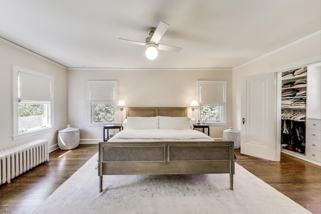 bedroom featuring radiator heating unit, crown molding, dark wood-style floors, and a ceiling fan