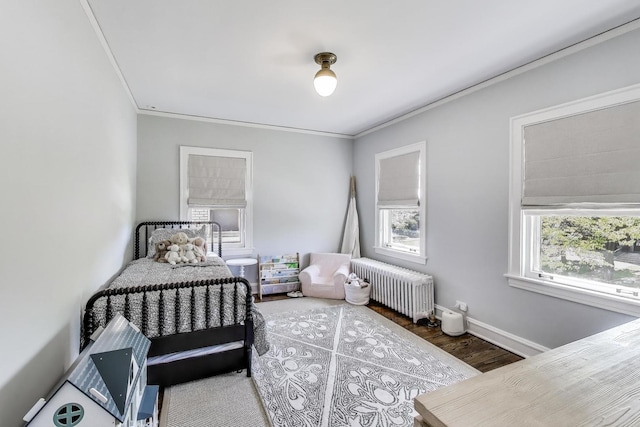 bedroom with radiator, ornamental molding, wood finished floors, and baseboards