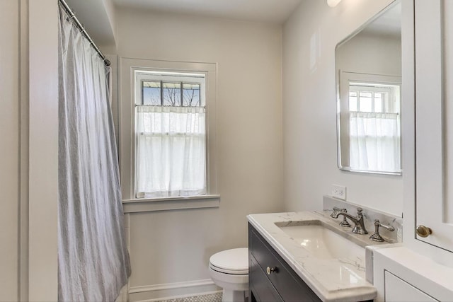 bathroom featuring toilet, vanity, and baseboards