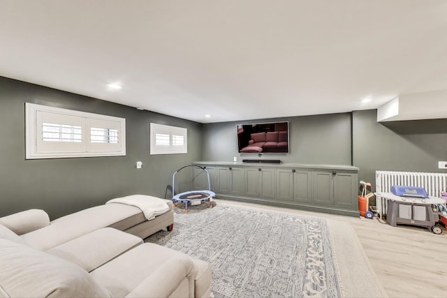 living area with radiator heating unit, light wood-style flooring, and recessed lighting