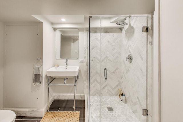 bathroom with a shower stall, tile patterned flooring, a sink, baseboards, and toilet